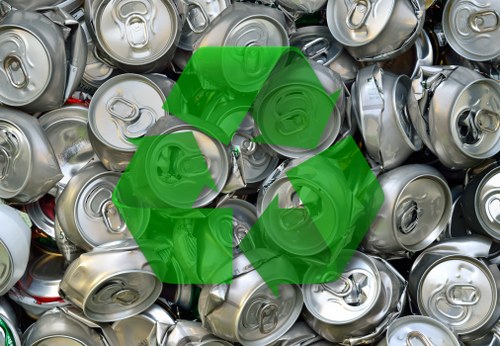 A close-up photograph of a large pile of used silver aluminum beverage cans, mostly with pull-tab lids, piled together in a disorganized stack. The cans exhibit various degrees of denting and wear, with some showing slight tarnish or scratching on their surfaces. The background shows more cans, creating a dense mass of metallic containers. The cans are stacked randomly, with some partially hidden behind others, and a few standing upright while others are tilted or laid on their sides. The overall scene emphasizes metallic textures and the reflective quality of the aluminum, typical of waste collected for recycling or removal in a rubbish clearance context. This image is relevant to rubbish removal services, such as those offered by Garden Clearance Finsbury Park, which manage waste including metal cans in urban and residential areas around Finsbury Park, London, postcodes N4 and N7.